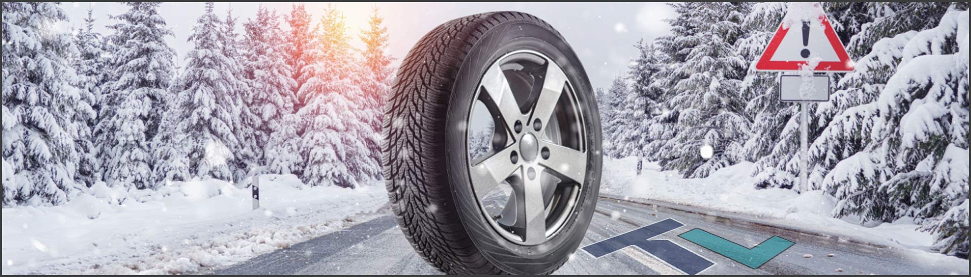 This image shows a car tire on a snowy road with snow on the trees which looks like a winter's day