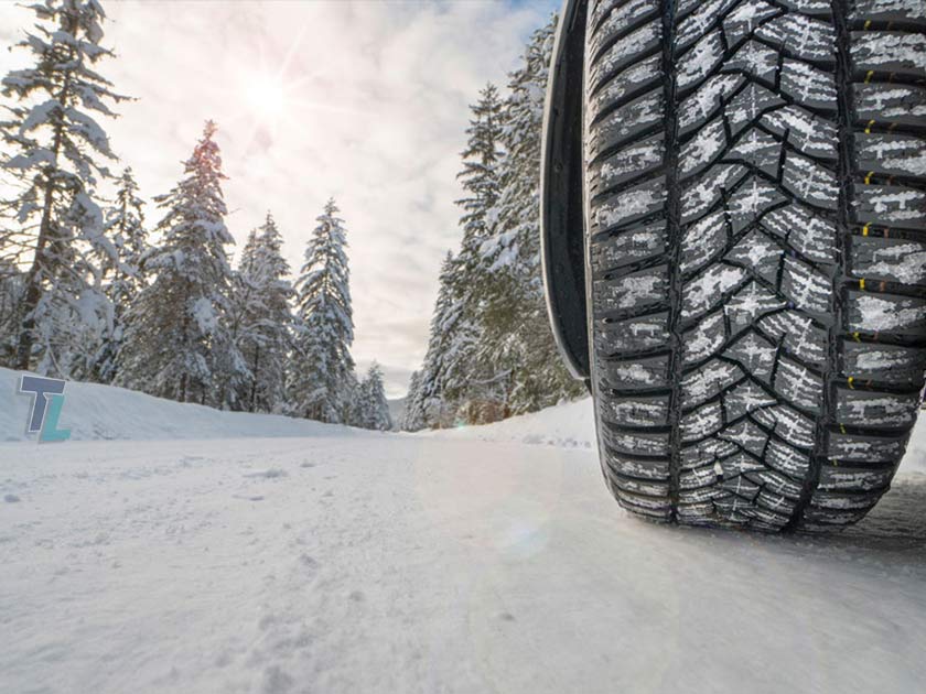 winter changeover services from Tireland Heavy Duty Automotive. Their image shows a tire with some on the threads and is on a snowy road with snow on the trees which looks like a winter's day in Kelowna